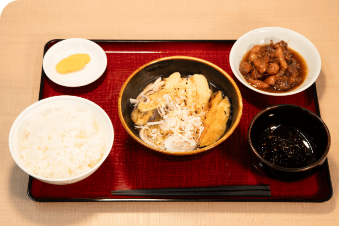 日替わり定食の写真です。お盆の上におかずが2品とご飯、汁物、漬物が乗せられています。